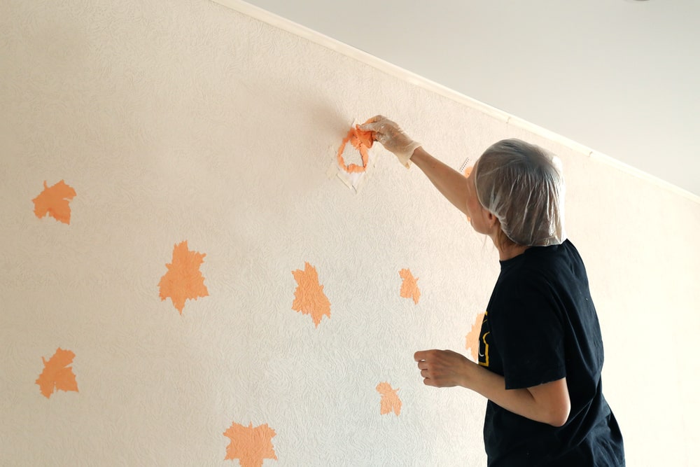 woman painting pattern on wall orange - Creative Ways to Add Texture to Your Home with Paint