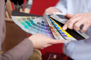 Interior decorator during a meeting with a client discussing paint colors from a set of colorful shades he holds in his hand. The Art of Color Matching