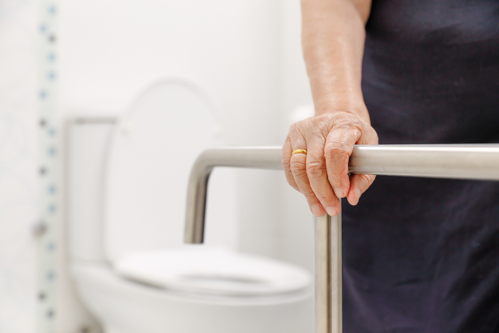 Elderly woman utilizing grab bars for support as part of Accessible Bathroom Remodeling for Seniors.